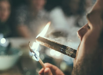 A perosn lighting a cigar with a match in a bar lounge space where a smoke eater would be beneficial.