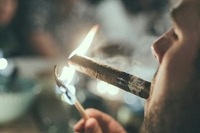 A person lighting a cigar in a bar lounge environment.